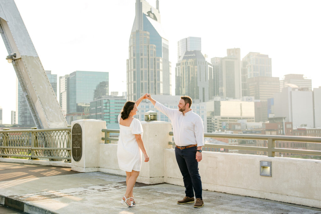 Man twirling his fiancée on the John Seigenthaler Pedestrian Bridge in Nashville, TN