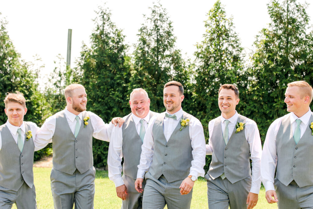 Groom walking and laughing with his groomsmen at Allenbrooke Farms