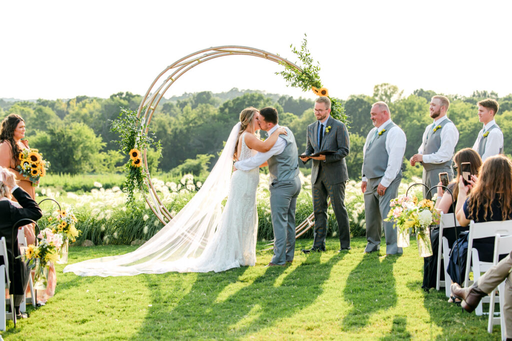 Bride and groom share their first kiss during their wedding ceremony at Allenbrooke Farms