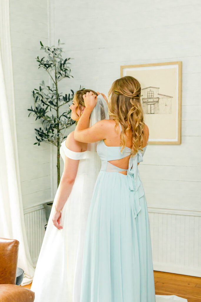 Bridesmaid helping the bride with her veil at Homestead Manor
