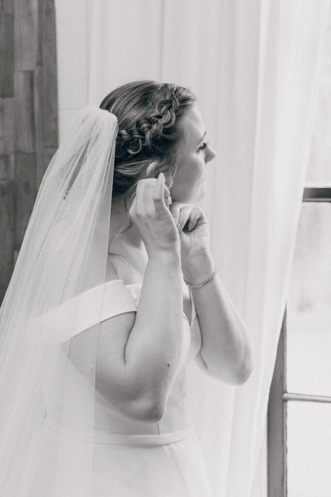 Black and white of bride putting her earrings on at Homestead Manor