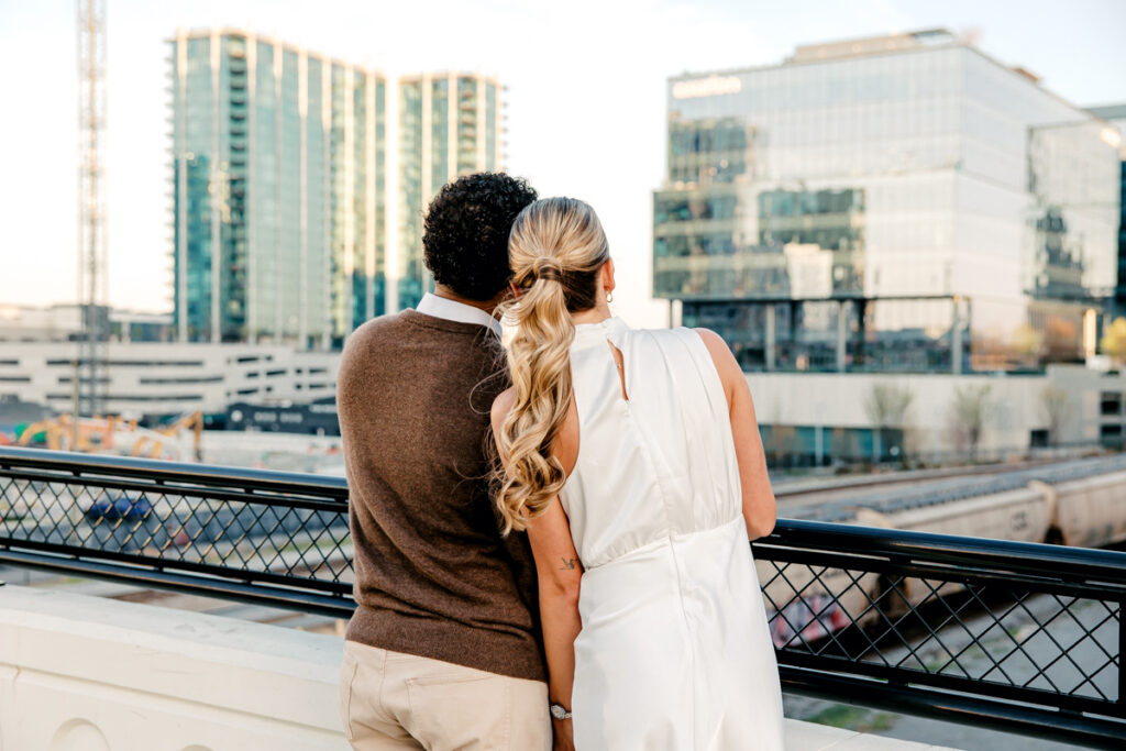 Couple standing on a bridge in Nashville, gazing into the distance during their Union Station engagement session