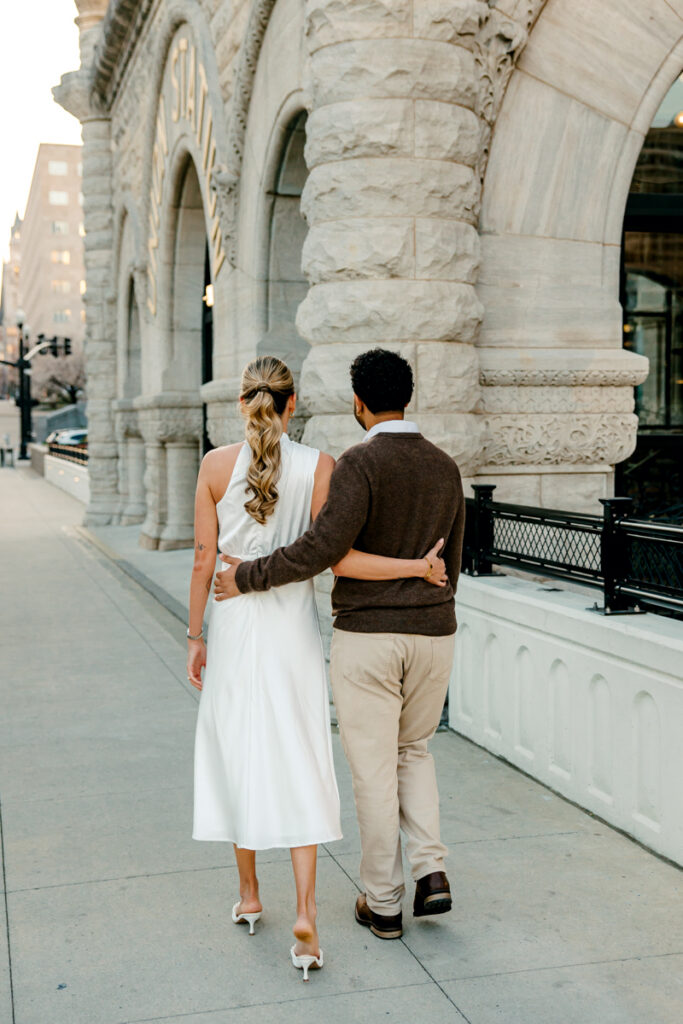 Couple with their arms wrapped around each other’s backs, walking down a street in downtown Nashville