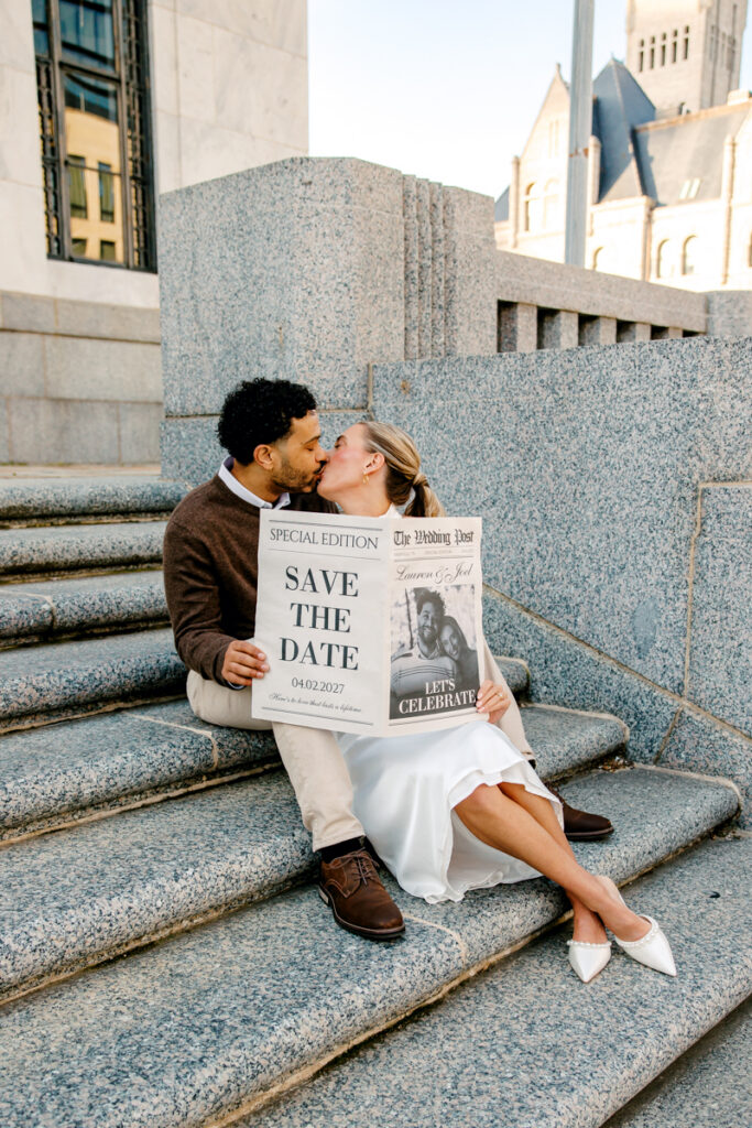 Couple holding their save the date newspaper