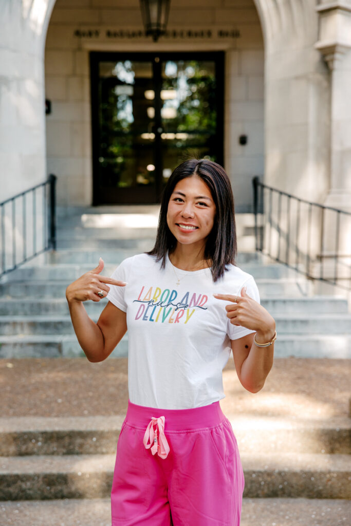 Nursing graduate pointing to her Labor and Delivery shirt during graduation portraits in Nashville