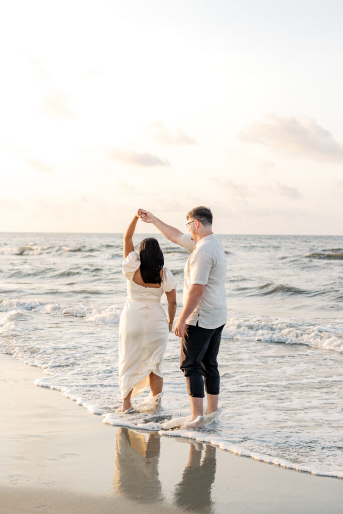 Man twirling his fiancée during a sunrise engagement session in Hilton Head