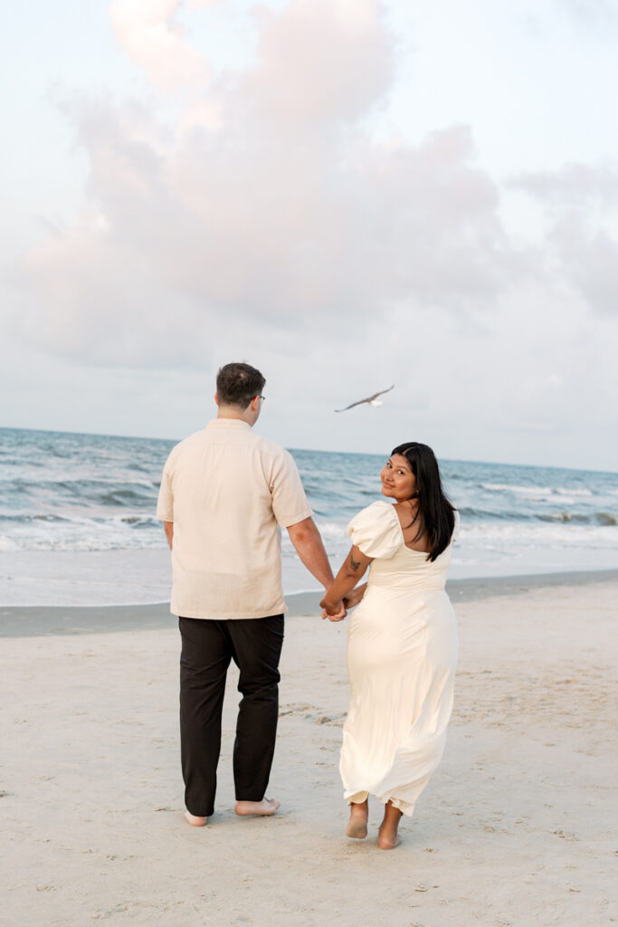 Couple walking along the beach during a sunrise engagement session at Hilton Head Island