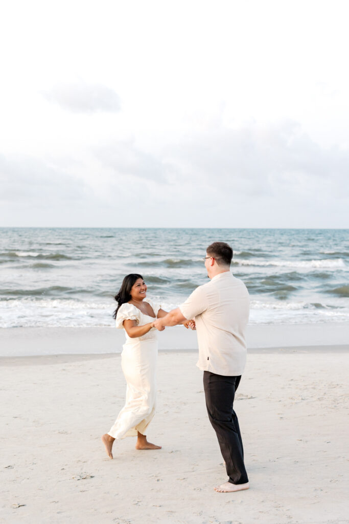 Playful moment of an engaged couple during a sunrise engagement session on the beach in Hilton Head