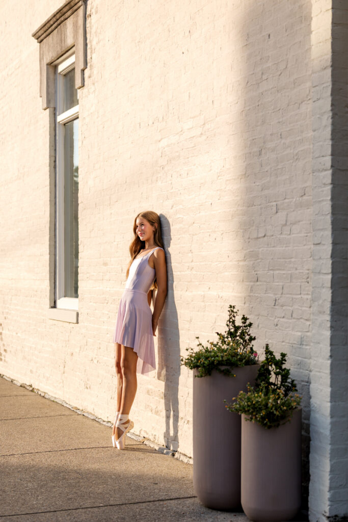 Ballet dancer leaning against a white brick wall in downtown Nashville.