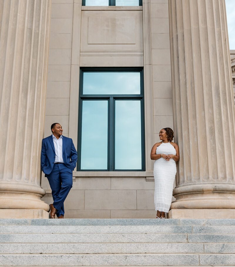 Engaged couple leaning against opposite columns during their Charlotte, NC engagement session